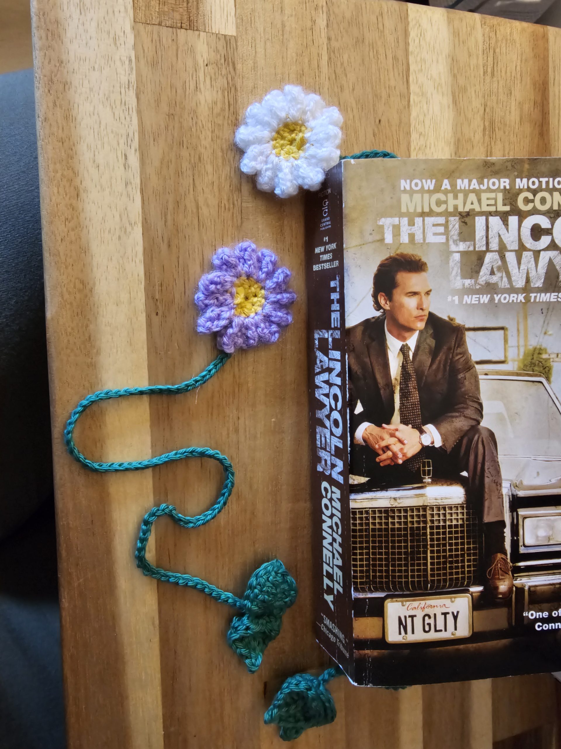 White and purple daisy bookmarks, with green stems inside a book